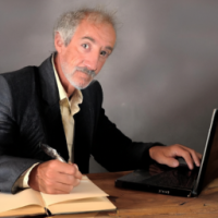 un homme  d'un certain âge, élégant, est en train de corriger un livre sur son ordinateur,
